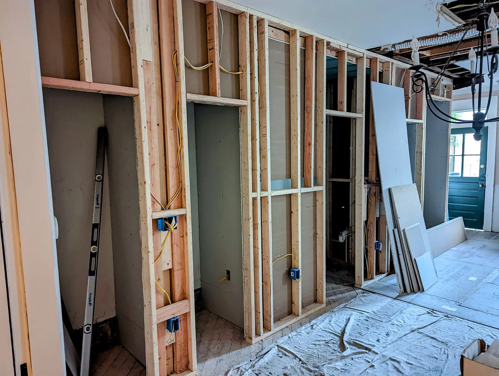 New interior wall framing during a home renovation, with drywall sheets stacked nearby