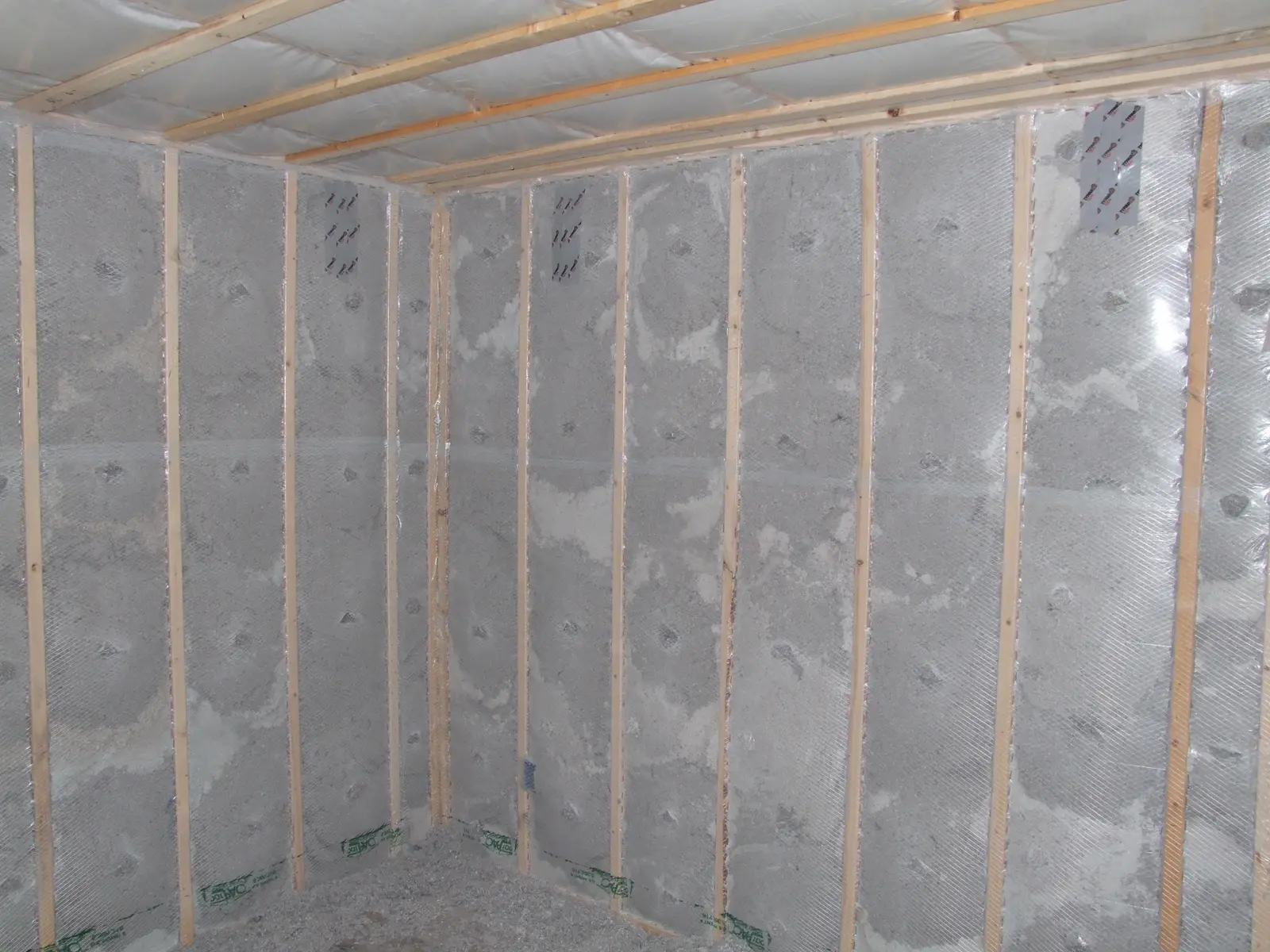 Framed lower-level walls insulated and covered with sheeting before drywall