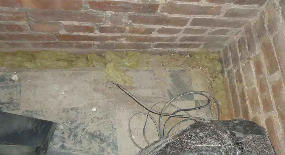 Mineral-wool insulation along the top of a brick foundation wall below the floor framing